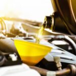 Garrafa de anticongelante rellenando el depósito de un coche con un embudo